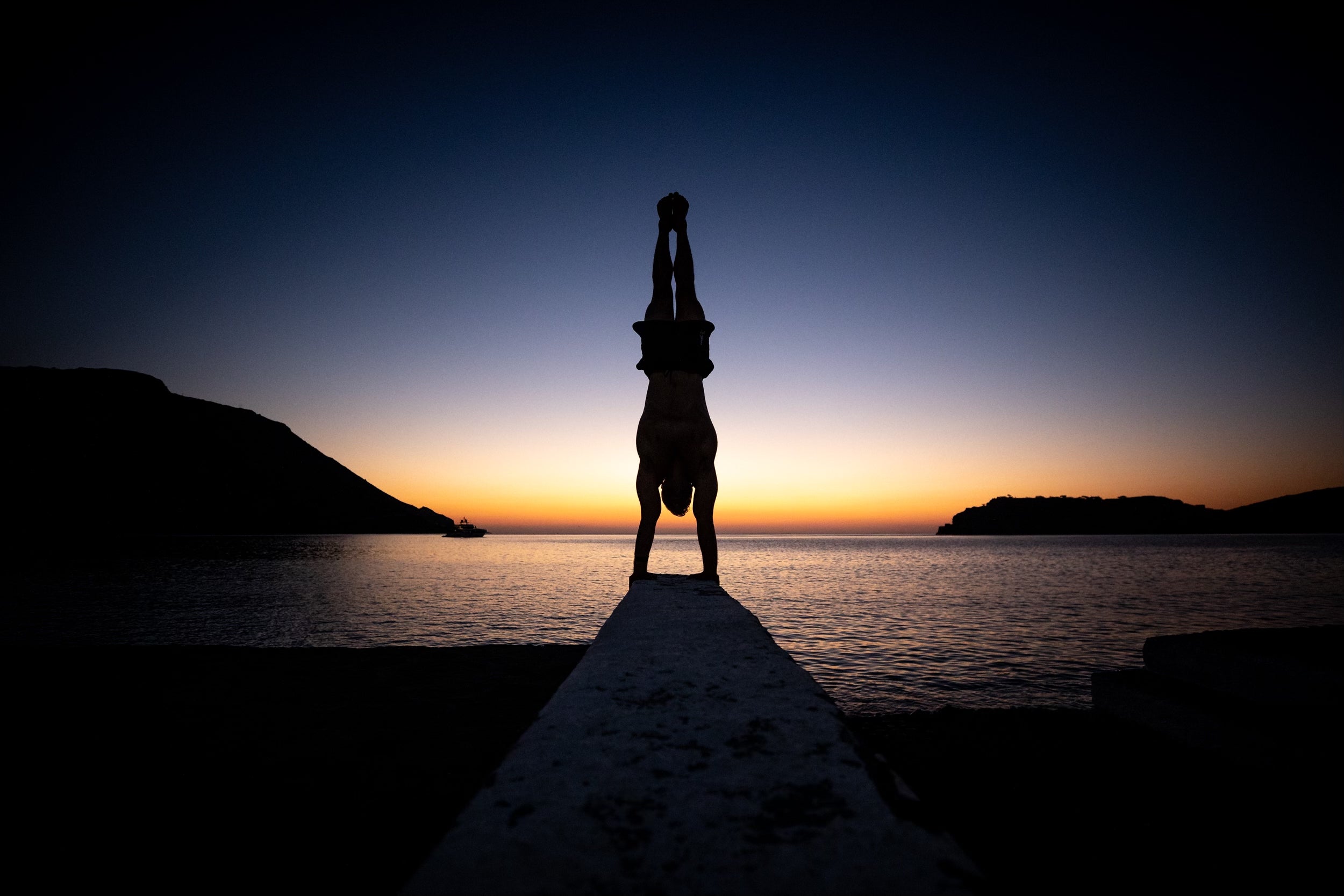 Photo of Dave Durante doing a handstand at sunrise in Crete, Greece. 