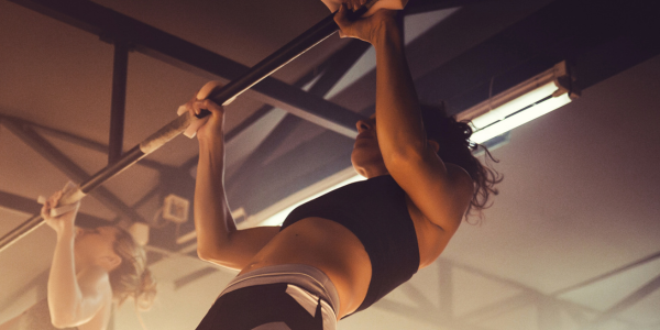 Woman performing a pull-up in a gym following the Get Your First Pull Up program in the Power Monkey Training app. 