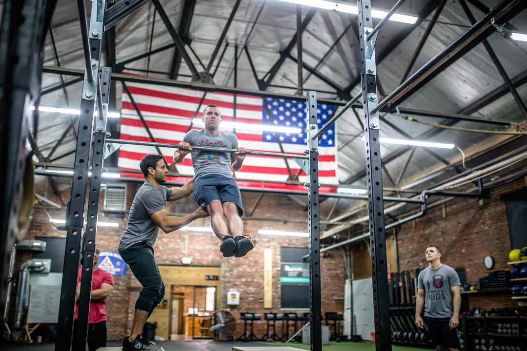 Photo of Dave Durante spotting an athlete performing a Chest to Bar at a Power Monkey Fitness Course. 