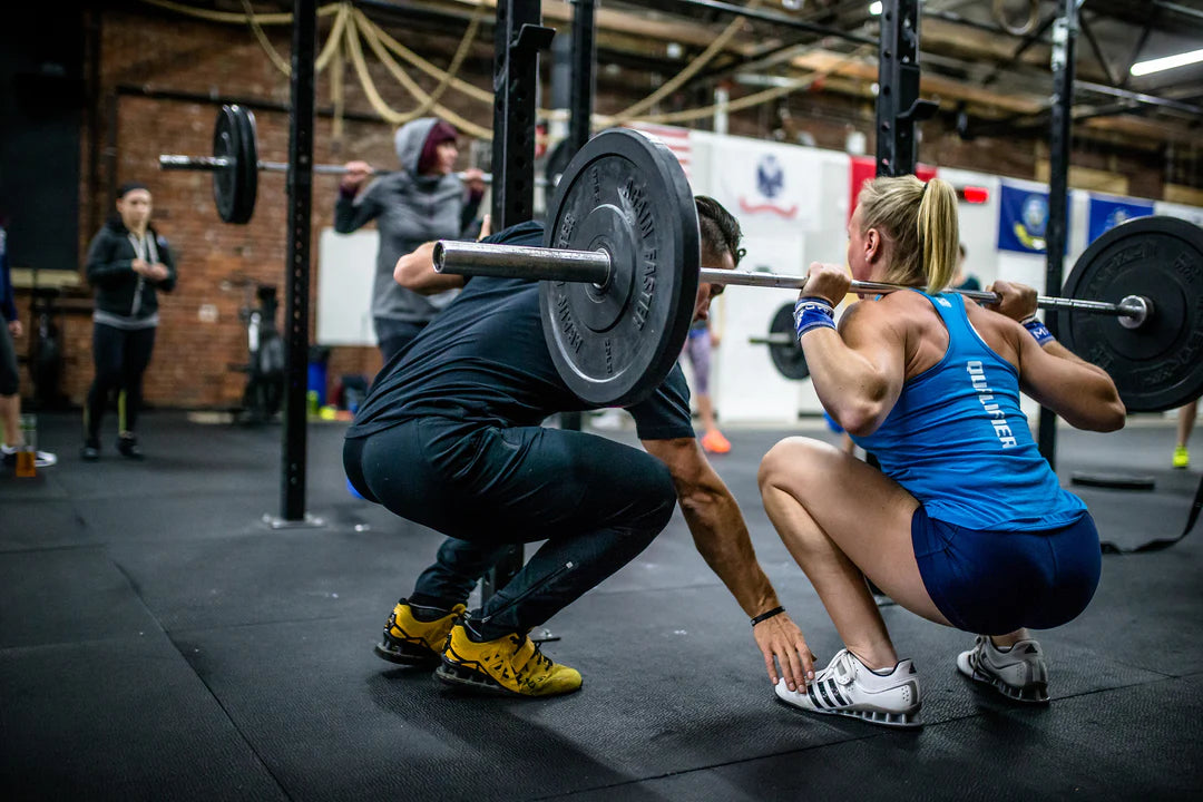 Photo of Mike Cerbus checking the positioning of an athlete performing a back squat at a Power Monkey Fitness course. 