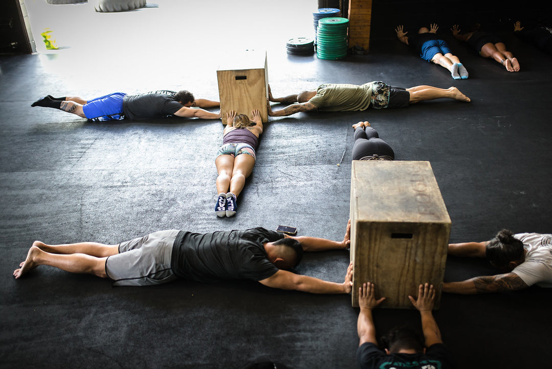 Group of people performing a body tightener exercise to practice handstands at a Power Monkey Fitness Course.