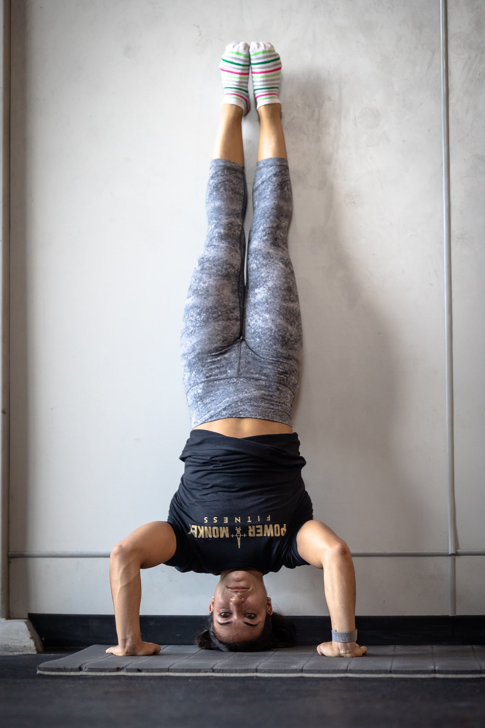 woman doing a handstand push-up in a gym as part of the power monkey training program