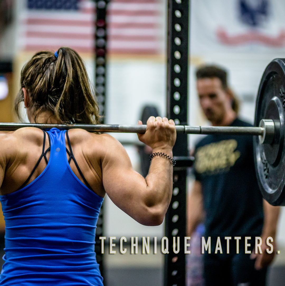 image of a woman performing a back squat as coach mike cerbus looks on.