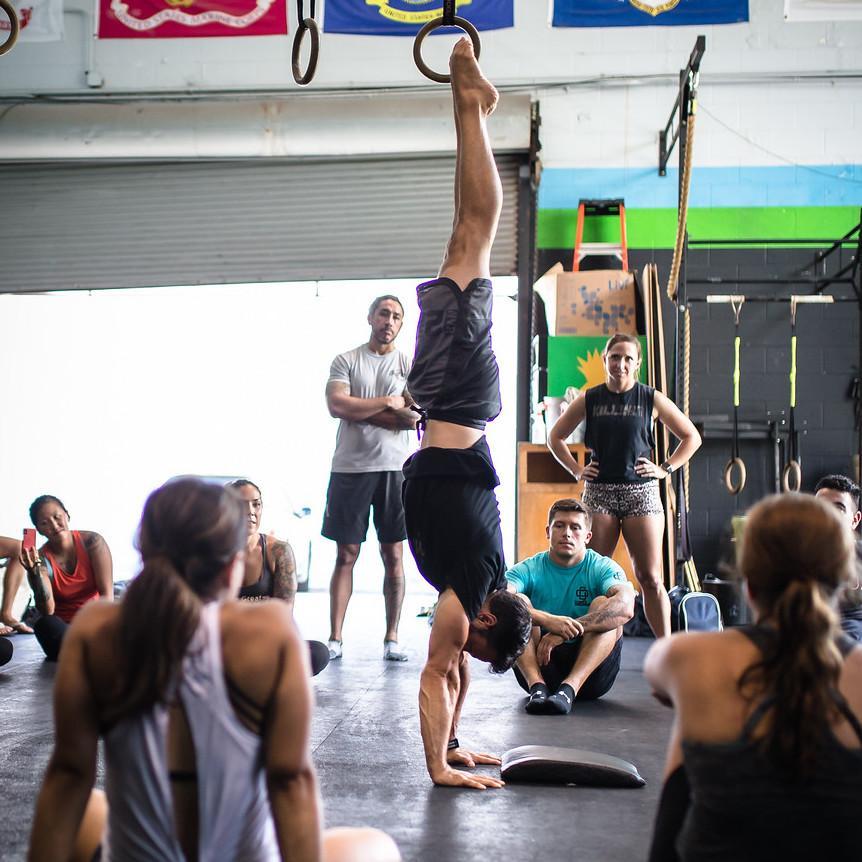 Image of Dave Durante performing a Handstand in front of a group of people at a Power Monkey Course.